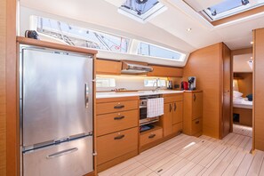 A modern kitchen with wooden cabinets, a stainless steel refrigerator, and a skylight. - Sun-Kissed Sailing Adventure in the Saronic Islands (Nea Peramos)
