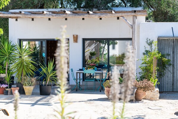 A patio with a table and chairs, surrounded by potted plants.