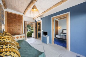 A bedroom with a bed, a TV, and a bathroom visible through an open door.