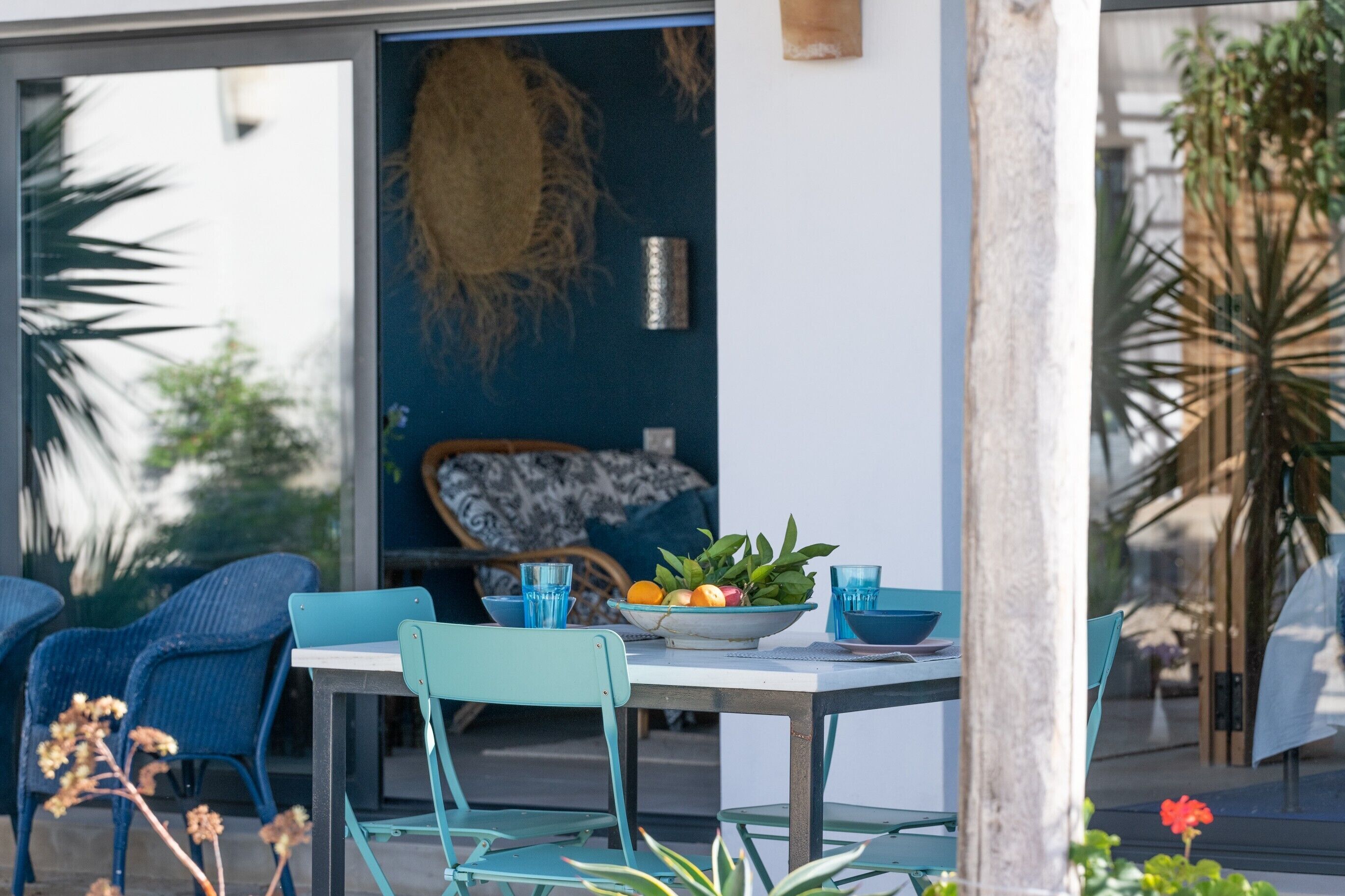 An outdoor dining area with a table, chairs, and a bowl of fruit.