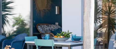 An outdoor dining area with a table, chairs, and a bowl of fruit.