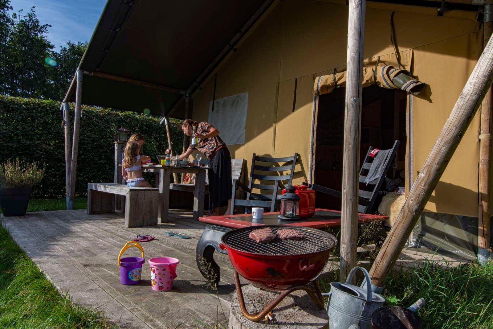 Un patio exterior con una mesa, sillas, una parrilla y una zona cubierta.