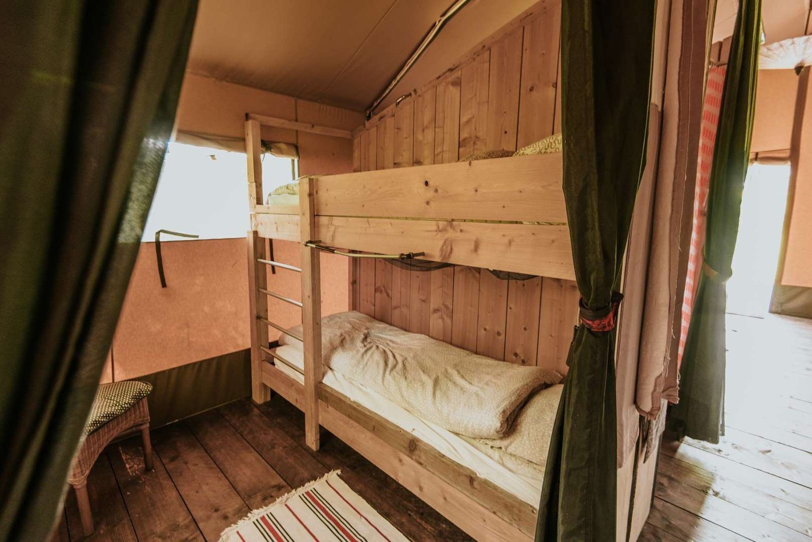 Une chambre avec un lit superposé, des murs en bois, une échelle et une petite chaise.