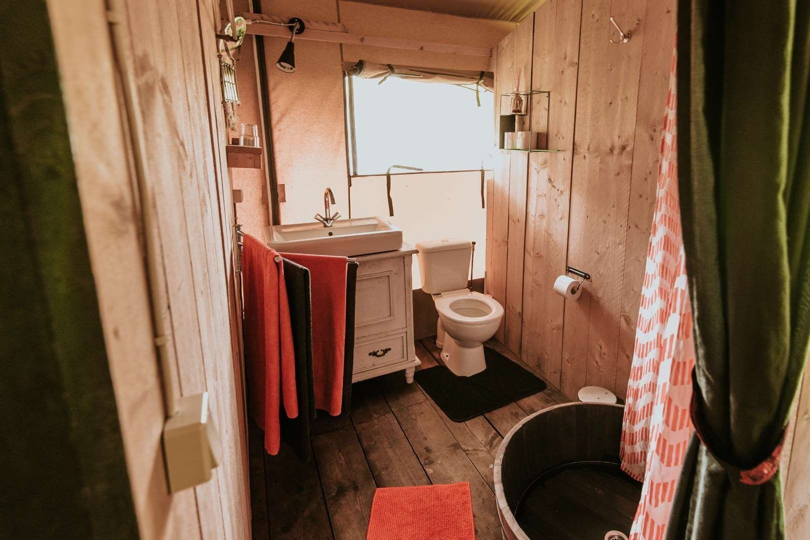 Une petite salle de bain au style rustique, avec un intérieur en bois, un lavabo, des toilettes et une petite baignoire.
