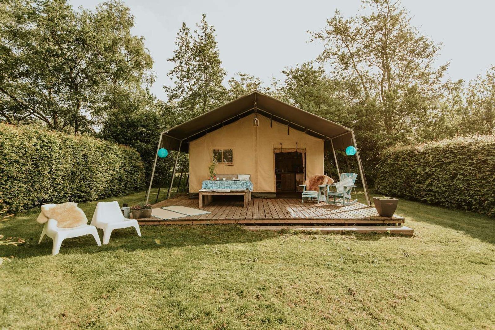 A cozy outdoor seating area with a table and chairs, a tent-like structure, and a small garden.