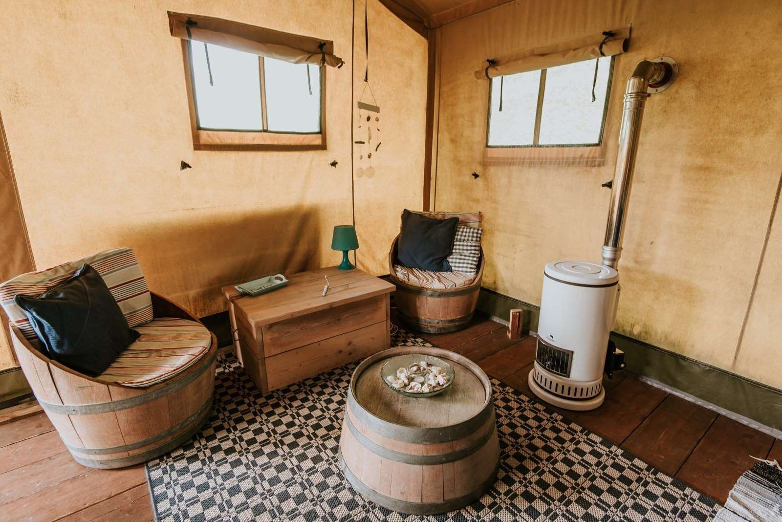 Une pièce rustique, meublée de meubles en bois, avec une petite table, deux fenêtres et un poêle à bois.