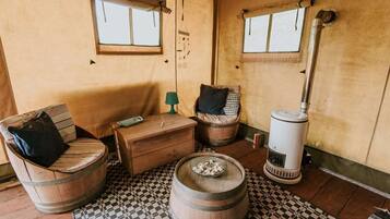 Une pièce rustique, meublée de meubles en bois, avec une petite table, deux fenêtres et un poêle à bois.