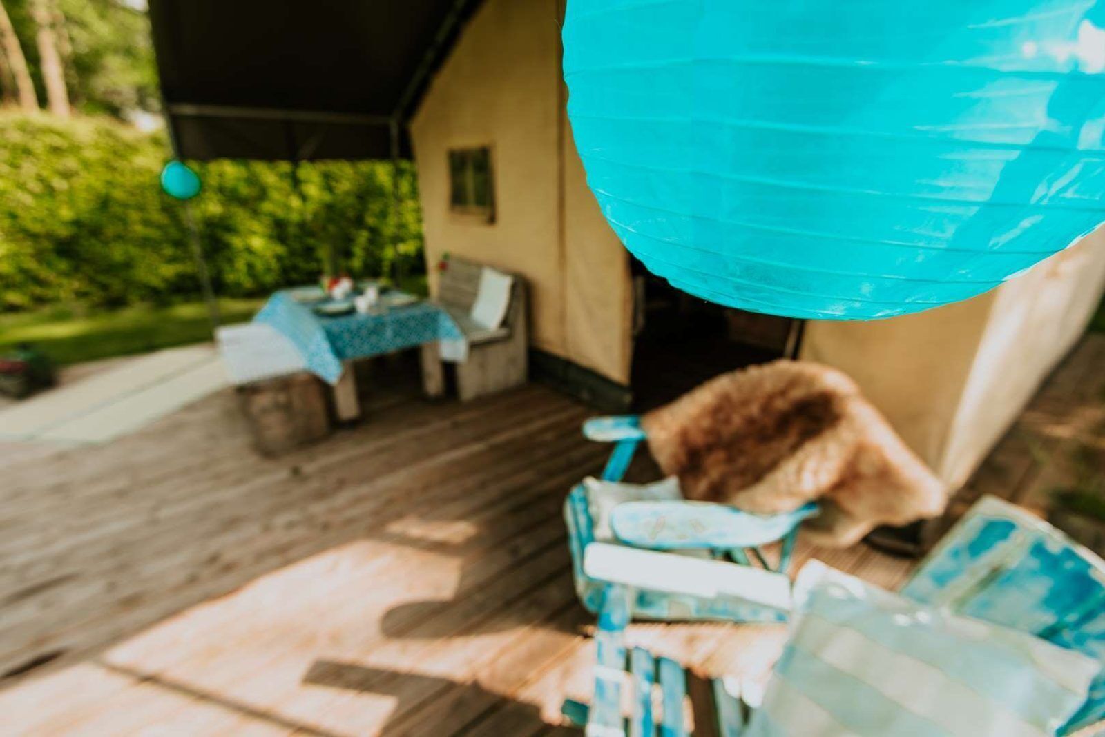 Een terras met buitenmeubilair, een tafel met een blauwe tafelkleed, en een huis op de achtergrond.