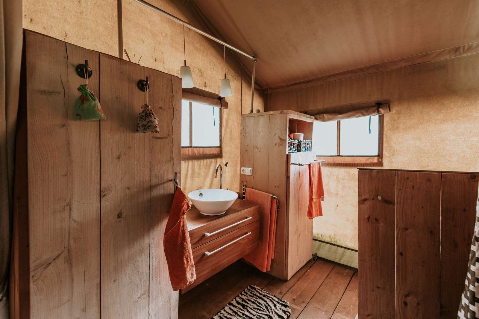 Une salle de bain rustique, aménagée dans une cabane en bois, avec un lavabo, un porte-serviettes et une fenêtre.