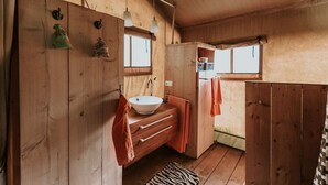 A wooden cabin bathroom with a sink, towel rack, and a window. - Kampari - Luxury Safari Tent - Out of Africa (Delfstrahuizen)
