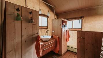 Une salle de bain rustique, aménagée dans une cabane en bois, avec un lavabo, un porte-serviettes et une fenêtre.