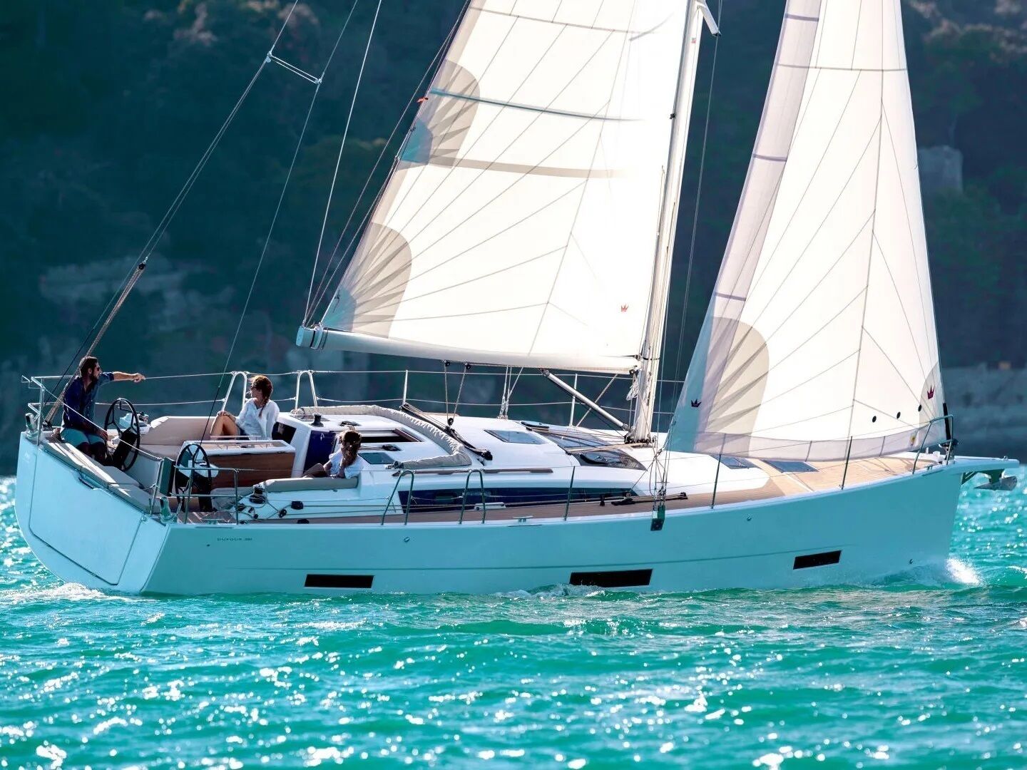 A sailboat with a cabin, a deck, and a person steering.