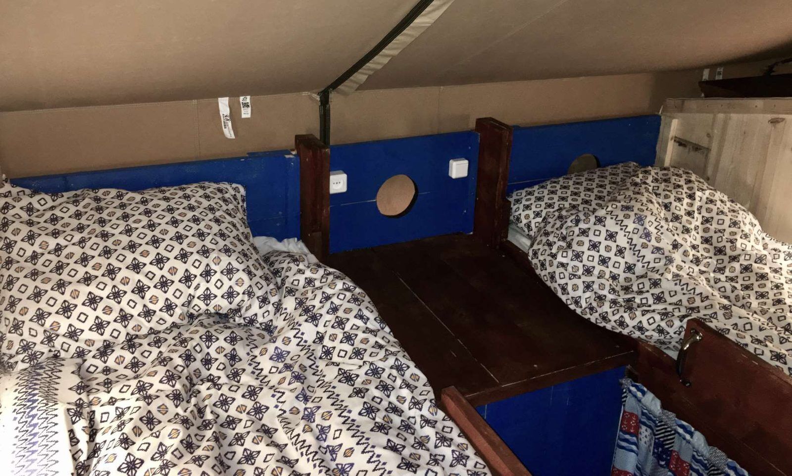 A bunk bed with patterned bedding, a wooden headboard, and a blue wall.