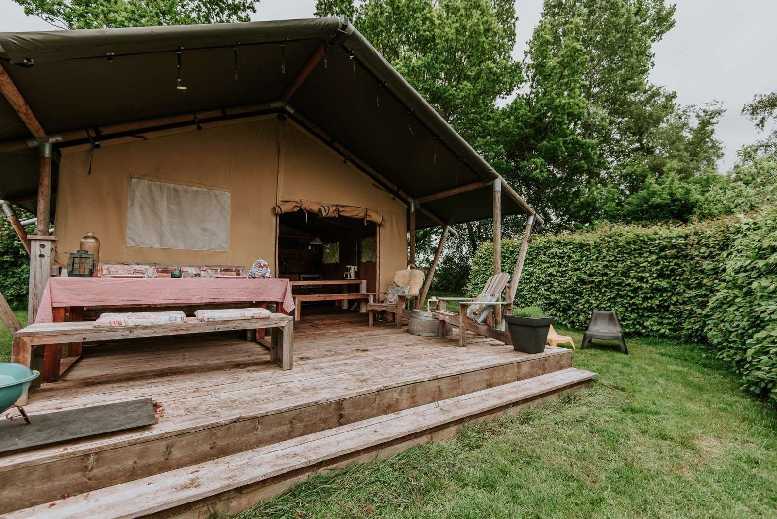 A rustic wooden structure with a covered porch, a table, benches, and outdoor seating.