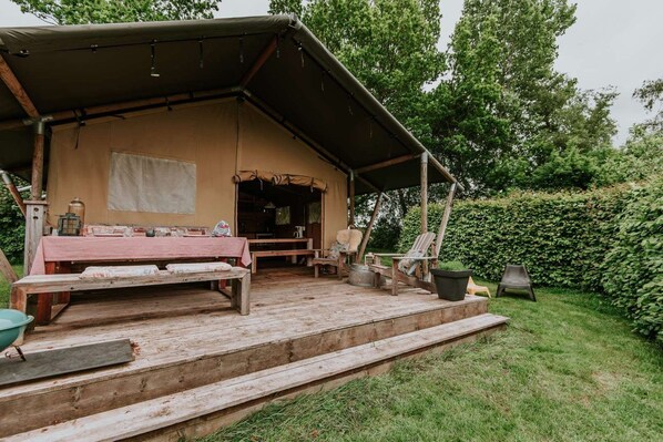 A rustic wooden structure with a covered porch, a table, benches, and outdoor seating.