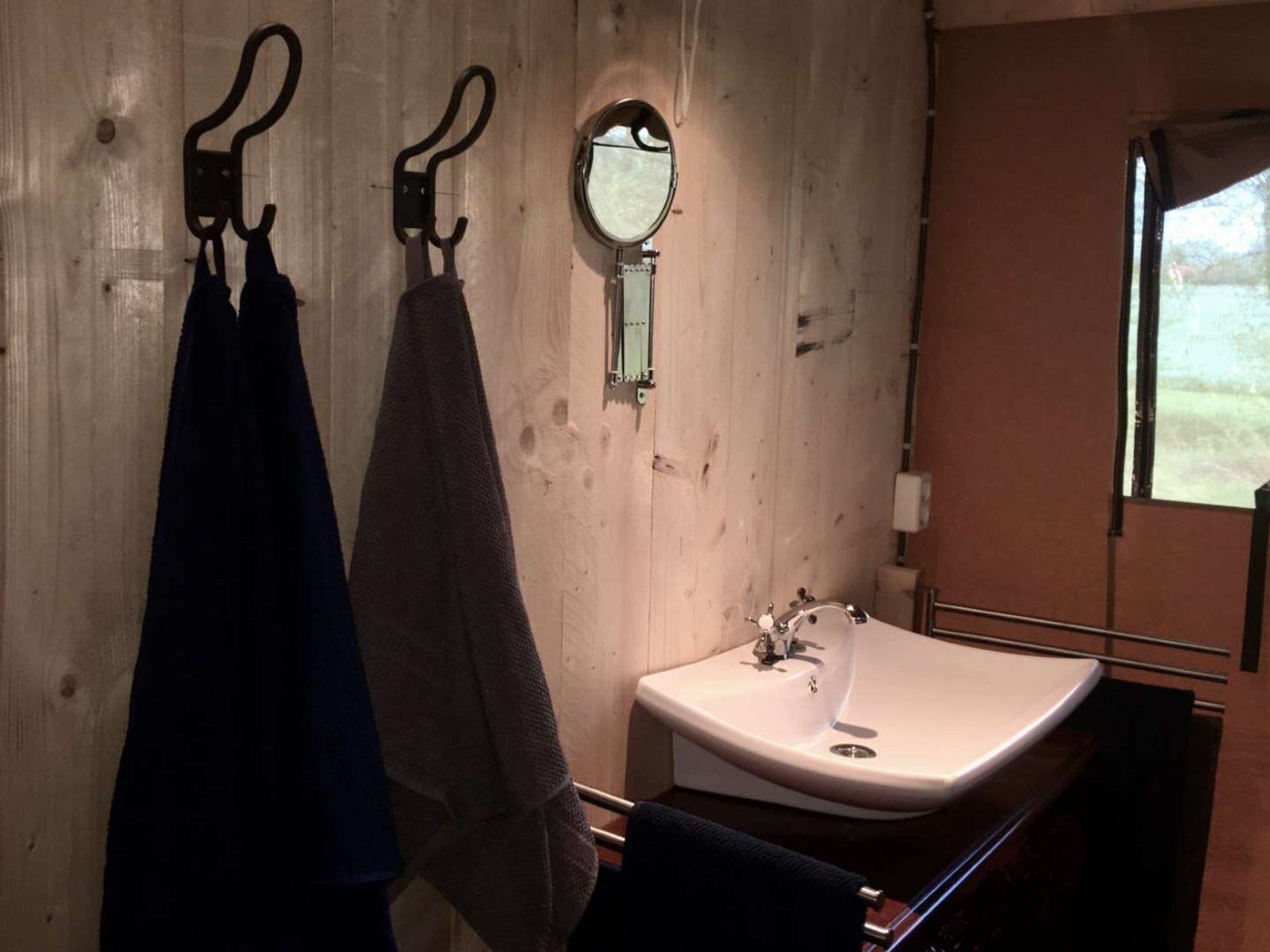 Une salle de bain avec des murs en bois, un lavabo et deux serviettes suspendues à des crochets.