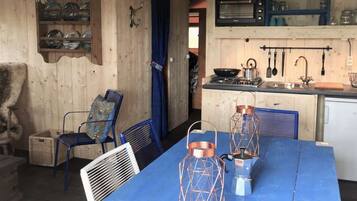 Une cuisine rustique aux murs en bois, avec une table bleue et des lanternes en cuivre.