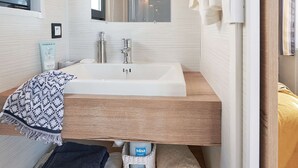 Ein Badezimmer mit einem weißen Waschbecken, einer Holzauskleidung und einem Handtuchhalter.