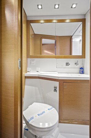A compact bathroom with a white toilet, a mirror above the sink, and a wooden vanity.