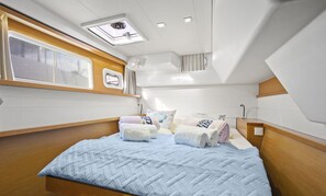 A compact, well-lit cabin with a bed, pillows, and a skylight.