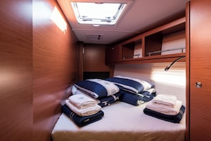 A compact, well-lit interior with a skylight, a bed with neatly folded towels, and wooden cabinetry. - Sun-Kissed Sailing Adventure in Sibenik, Croatia (Primošten)