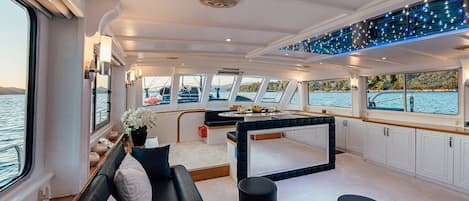 Un interior moderno con sofá, mesa de comedor y zona de cocina en un barco.
