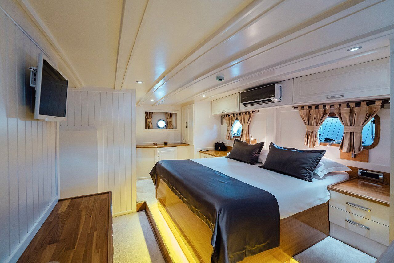 A bedroom with a bed, bedside tables, a TV, and an air conditioning unit.