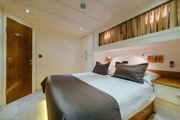 A bedroom with a bed, bedside tables, a wooden door, and a light fixture. - Sun-Kissed Sailing Adventure in Split-Dalmatia, Croatia (Marina)