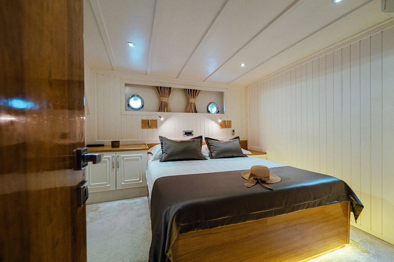 Une chambre à coucher comprenant un lit, des tables de chevet, une armoire et un luminaire au plafond.