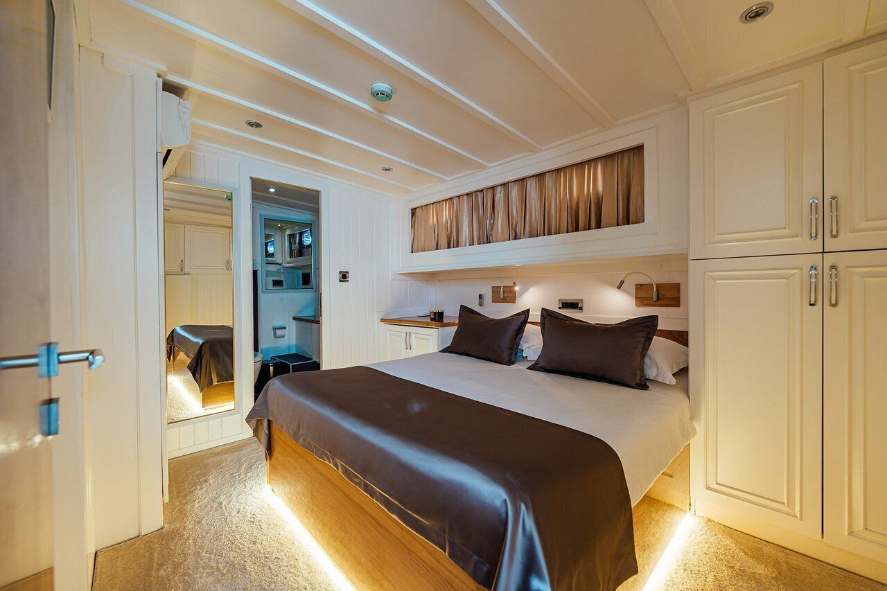 A hotel room with a large bed, a wardrobe, a vanity, and a bathroom visible through an open door.