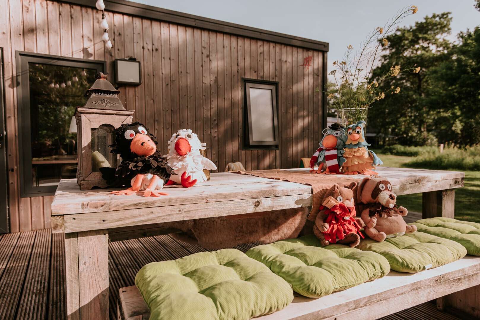 A wooden picnic table with plush toys and a lantern.