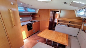 A compact kitchen with a dining area, a small oven, and a sink. - Sun-Kissed Sailing Adventure in Zadar, Croatia (Bibinje)