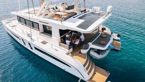 A large yacht with a covered dining area, a lounge with seating, and a deck with a small table and chairs. - Sun-kissed Sailing Adventure in Split-Dalmatia, Croatia (Seget Donji)