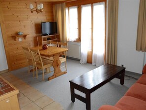 Ein Holzinterieur mit Esstisch, Stühlen, Fernseher und einer Couch.