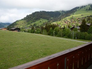 Ländliche Landschaft mit Häusern an einem Hügel, einer Straße und einem Wiesenfeld.
