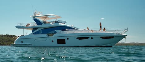 A large yacht with multiple decks and a helipad, floating on calm waters.