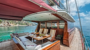 A boat deck with a dining area, seating, and a view of the water. - Sun-Kissed Sailing Adventure in Mlini, Croatia (Srebreno)