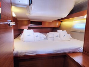 A compact cabin with a bed, pillows, and neatly folded towels. - Sun-Kissed Sailing Adventure in Split, Croatia (Kaštel Gomilica)