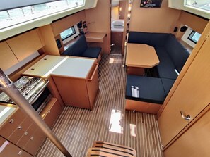 A compact interior with a dining area, a small kitchenette, and a seating area with a view. - Sun-Kissed Sailing Adventure in Zadar, Croatia (Bibinje)
