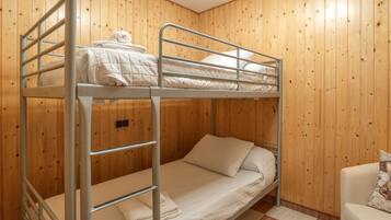 A bunk bed room with wooden walls, a checkered floor, and a white chair.