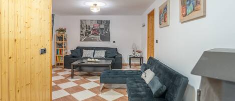 A living room with a checkered floor, a sofa, a coffee table, and a painting on the wall.