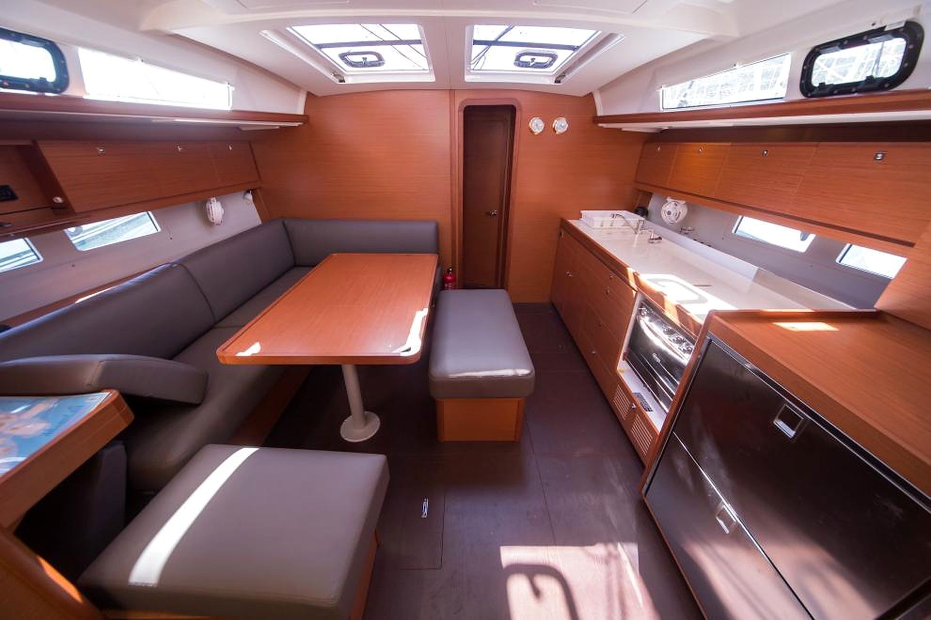 A compact galley with a bench, a small table, and a refrigerator.