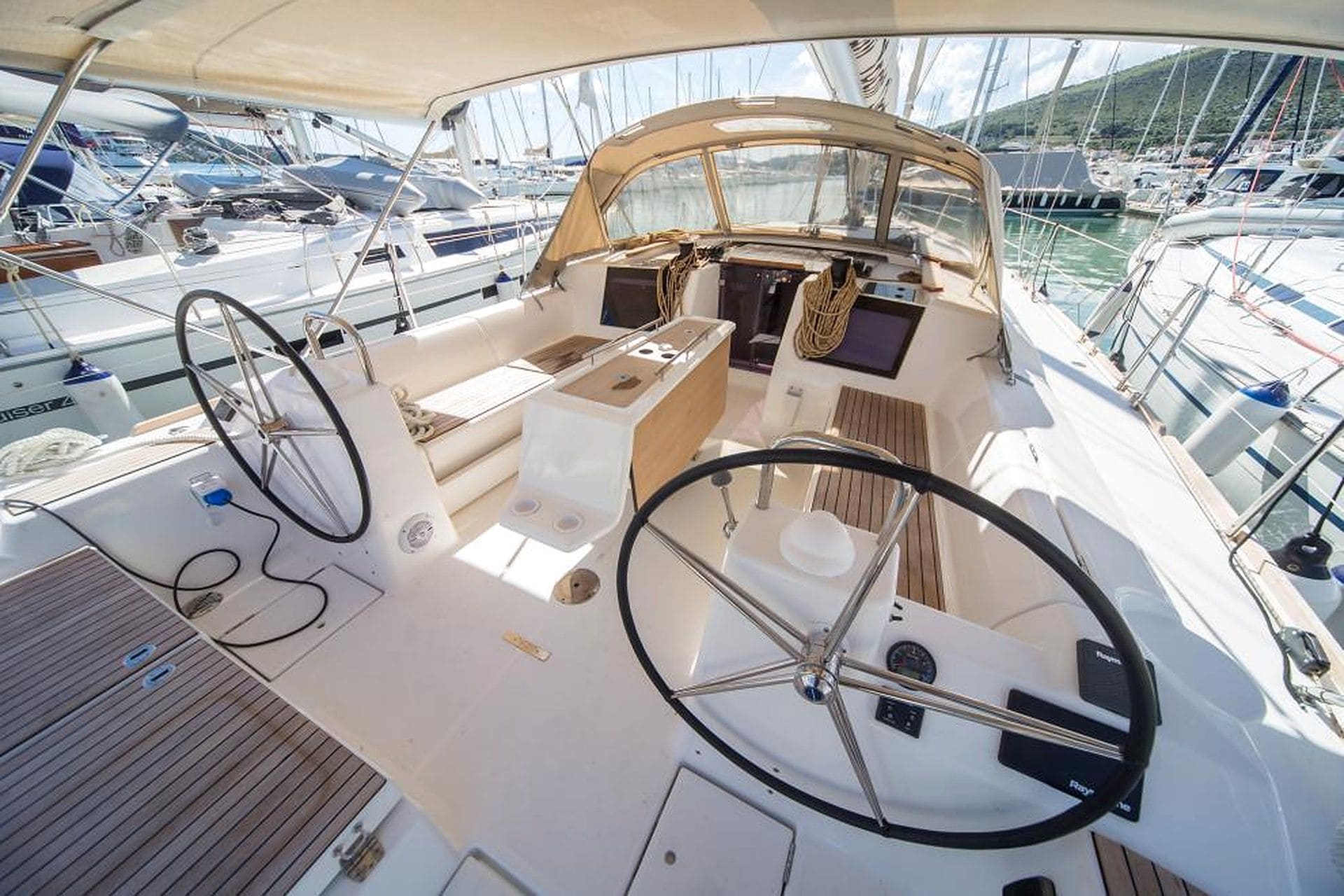 A boat's deck with a steering wheel, control panel, and seating area.