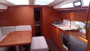 A compact kitchen with a dining area, wooden cabinets, and a small refrigerator. - Sun-Kissed Sailing in Mar de Cortez: A Baja California Sur Beach Experience (La Paz)