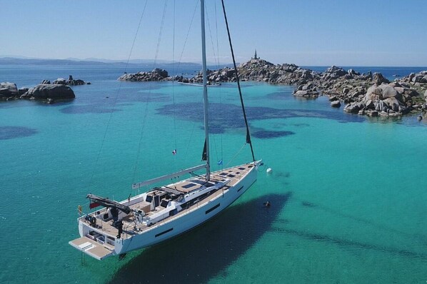 Ein Segelboot ankert in der Nähe von felsigen Ufern mit klarem, türkisblauem Wasser.