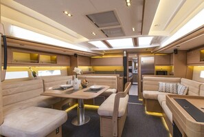 A compact RV interior with a dining area, seating, and a kitchenette.