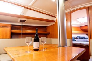 A wooden table with a bottle of Juricic wine and two glasses on a boat interior.
