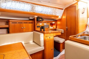 A compact, well-lit interior with a wooden vanity, a small sink, and a cushioned seating area.