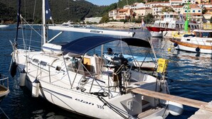 Un velero amarrado en un puerto deportivo con vistas a un pueblo costero al fondo.
