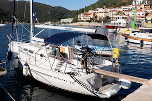 Un voilier est amarré dans une marina, avec une vue sur une ville côtière en arrière-plan.